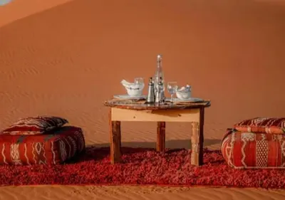a table with a tea set on top of a red rug at Sahara horizon Camp in Merzouga