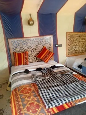 a bed with colorful blankets and pillows on it at Luxury Camp Sahara in Merzouga