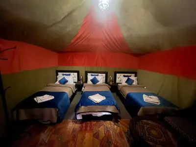 a room with three beds in a tent at luxury camp desert ideal in Merzouga