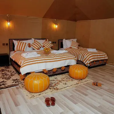 two beds in a room with pumpkins on the floor at luxury camp desert ideal in Merzouga