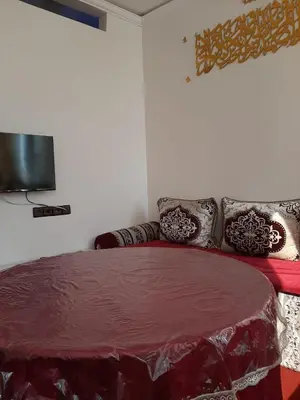a bedroom with a red bed with pillows and a television at Dar Igri in Ourika