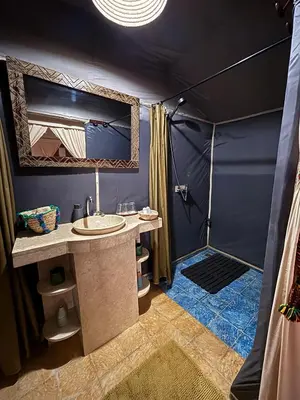 a bathroom with a shower and a sink in a tent at Touareg spirit luxury Camp in Merzouga