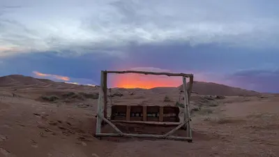 an object in the desert with the sunset in the background at Touareg spirit luxury Camp in Merzouga