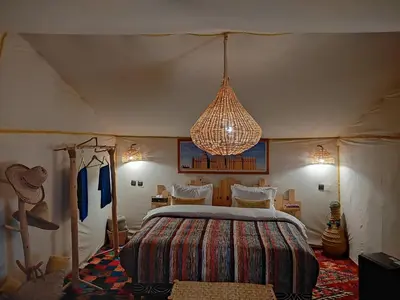 a bedroom with a bed and a chandelier at Touareg spirit luxury Camp in Merzouga