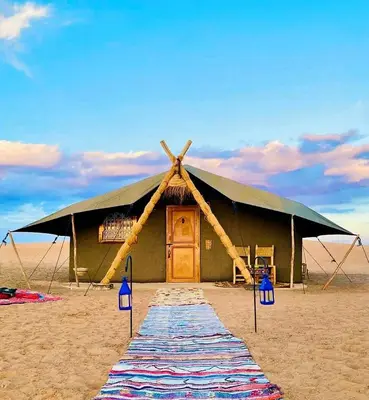 a large tent on the beach with a blue sky at Touareg spirit luxury Camp in Merzouga