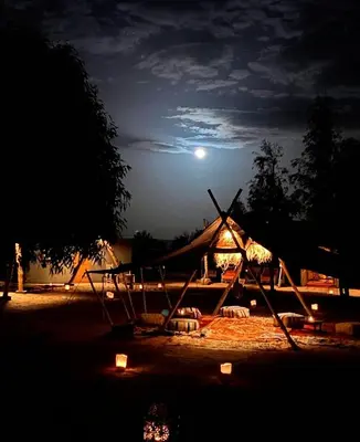 a tent at night with the moon in the sky at Touareg spirit luxury Camp in Merzouga