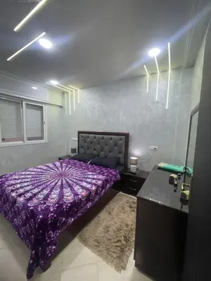 a bedroom with a purple bed and a mirror at Dans un bâtiment in Meknès
