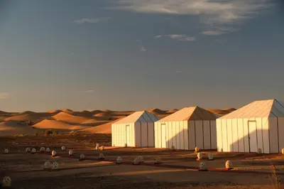 a group of white buildings in the desert at Infinity Camp Morocco in Mfis