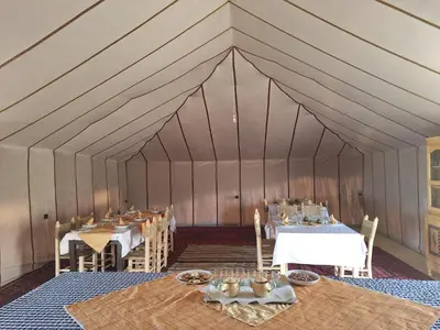 a dining room with tables and chairs in a tent at Infinity Camp Morocco in Mfis