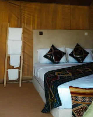 a bedroom with a bed with pillows and a chair at Infinity Camp Morocco in Mfis