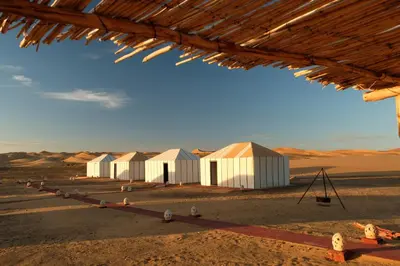 a group of white buildings in the desert at Infinity Camp Morocco in Mfis