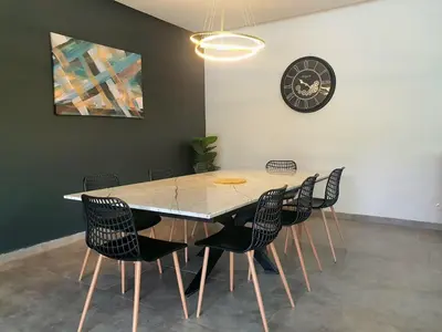 a dining room table with chairs and a clock on the wall at Not overlooked villa with heated pool 4 suites in Oulad Akkou