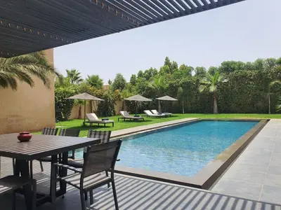 a patio with a table and a swimming pool at Not overlooked villa with heated pool 4 suites in Oulad Akkou