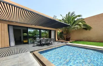 a swimming pool in front of a house with a table and chairs at Not overlooked villa with heated pool 4 suites in Oulad Akkou