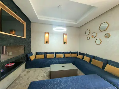 a living room with a blue couch and a table at Not overlooked villa with heated pool 4 suites in Oulad Akkou