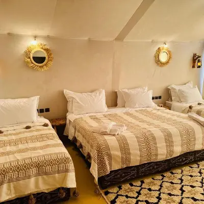 a bedroom with two beds and a mirror on the wall at Sand Dunes Luxury Camp in Merzouga
