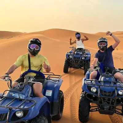 three people riding on quad bikes in the desert at Sand Dunes Luxury Camp in Merzouga