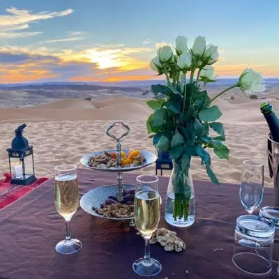 a table with wine glasses and a vase of flowers at Sand Dunes Luxury Camp in Merzouga