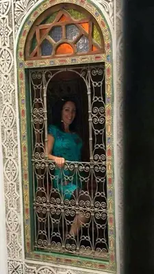 a woman sitting on a gate in a window at Dar lmallouki 2 in Fès