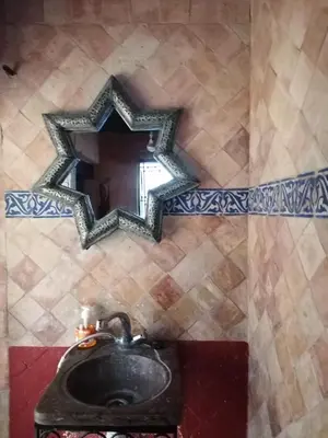 a bathroom with a sink and a mirror on a wall at Dar lmallouki 2 in Fès