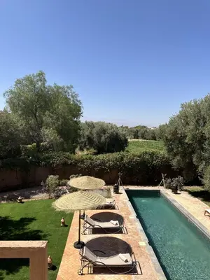 a swimming pool with chairs and umbrellas next to a pool at Villa Hania 4 chambres avec piscine in Heddad