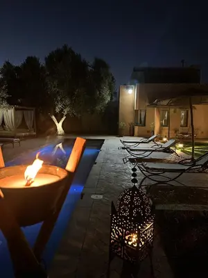 a patio with a fire pit at night at Villa Hania 4 chambres avec piscine in Heddad