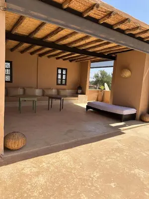 an outdoor patio with benches and tables in a building at Villa Hania 4 chambres avec piscine in Heddad