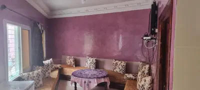 a living room with purple walls and a table at منزل باهية in Moulay Yacoub