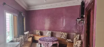 a living room with purple walls and a table at منزل باهية in Moulay Yacoub