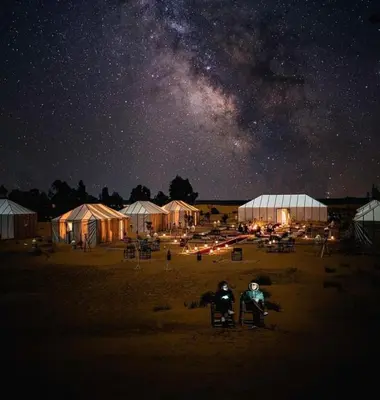 two people sitting in chairs under the milky way at night at Merzouga Marvelous Camp in Merzouga