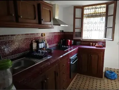 a kitchen with wooden cabinets and a sink and a window at Appartement privé Medina in Fès