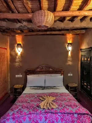 a bedroom with a large bed with a towel on it at Riad La Perle Tamnougalte in Agdz