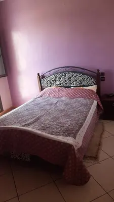 a bed in a bedroom with a purple wall at Appartement Fascinant à Meknès in Meknès
