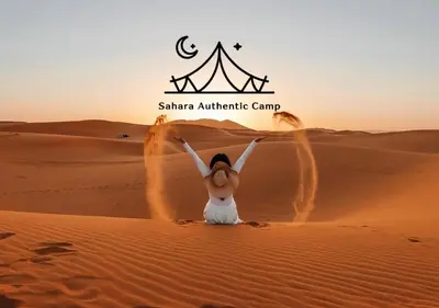 a woman in the desert with a tent in the background at Sahara Authentic Camp in Merzouga