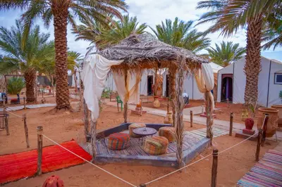 a tent in the middle of a desert with palm trees at Sahara Garden Luxury Camp in Merzouga