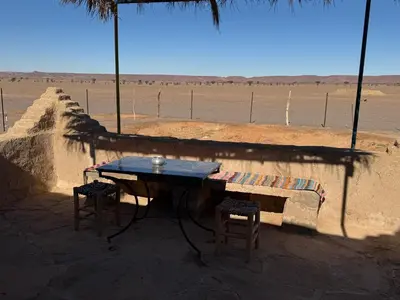 a table and two stools sitting in front of a wall at Guest House For Rent Merzane in Merzane