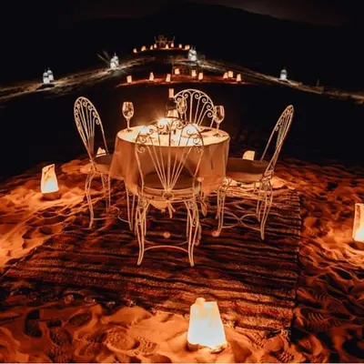 a table and chairs with a ship in the background at Dream Desert Camp in Merzouga