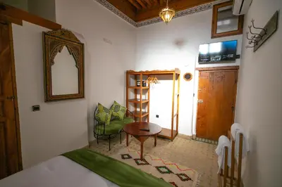 a bedroom with a bed and a table and a mirror at Riad Fes la Mama - Rooftop in Fès