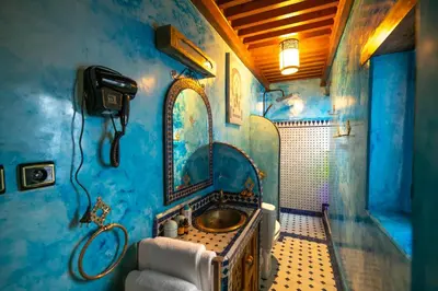 a blue bathroom with a sink and a mirror at Riad Fes la Mama - Rooftop in Fès