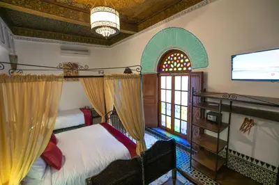 a bedroom with a bed and a tv and a window at Riad Fes la Mama - Rooftop in Fès