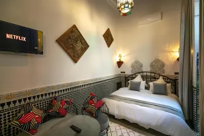 a bedroom with two beds and a tv on the wall at Riad Fes la Mama - Rooftop in Fès