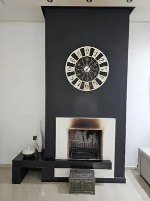 a fireplace with a clock on a black wall at Villa in Fès