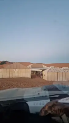 a view of a desert with buildings in the distance at Authentic Sahara Desert Camps in Merzouga