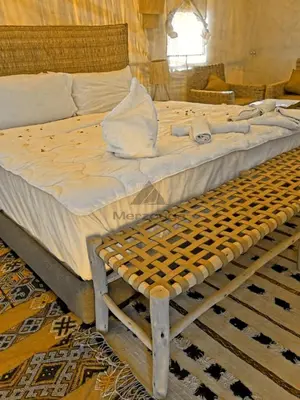 a large bed with a wooden frame in a room at Merzouga Luxurious Sahara Camps in Merzouga
