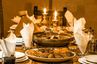 a table with plates of food and candles on it at Merzouga Luxurious Sahara Camps in Merzouga