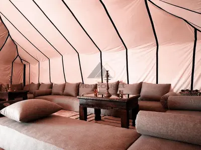 a room with a couch and a table in a tent at Merzouga Luxurious Sahara Camps in Merzouga