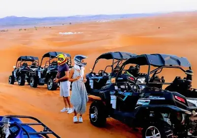 a group of people standing in the desert with atvs at Mystic Dunes Camp & desert activities in Merzouga