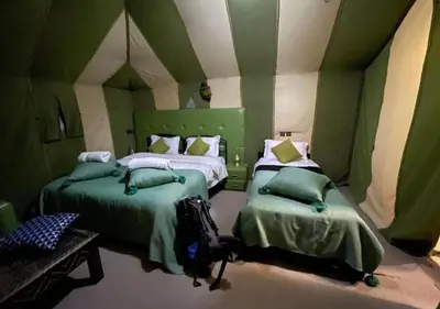 a green room with two beds and a table at Mystic Dunes Camp & desert activities in Merzouga