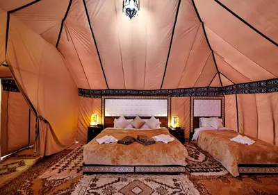 a bedroom with two beds in a tent at Merzouga Formidable camp in Merzouga
