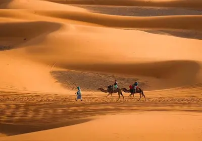 two people are riding camels in the desert at Merzouga Formidable camp in Merzouga